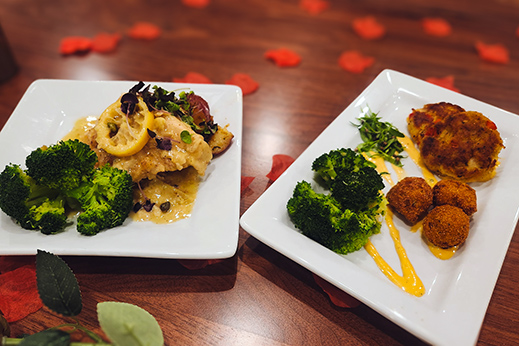 Two plates of chef-prepared dishes, surrounded by rose petals for a Valentine's dinner.