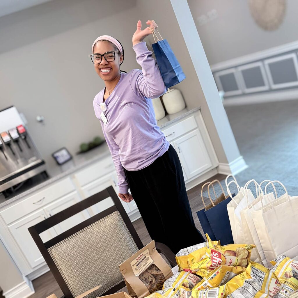 A team member at Vitalia Highland Heights smiles brightly, holding a gift bag.