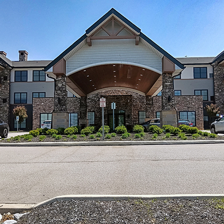 The front entry exterior of Vitalia Highland Heights, showcasing landscaping with mulch beds and many plants.